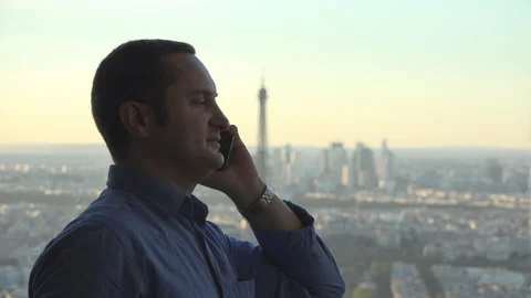 Man talks on mobile phone, Paris Eiffel tower in background Stock Footage 263988651