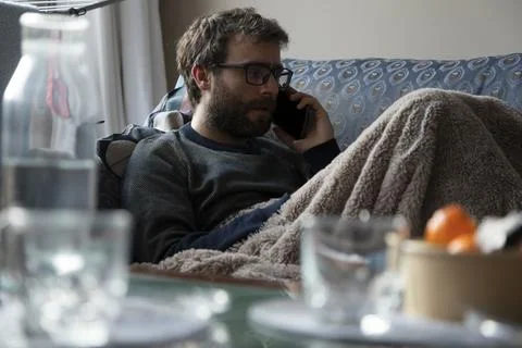 A man talks on the mobile phone while resting on the sofa Stock Photos