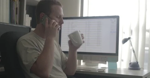 Man talks on phone and drinks tea at work 库存影片 78037356