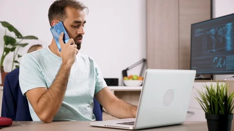 Man talks on the phone and types on the computer while his girlfriend is playing Stock Footage 95115514