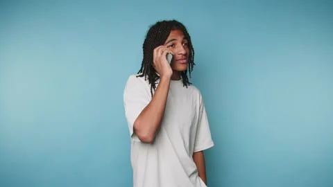 Man talks on the phone in front of a blue background while smiling during a.. Stock Footage 328248762