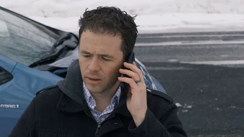 Man talks on phone frustrated as camera pans to show wrecked car Stockbeeldmateriaal 104268425