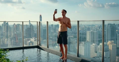 Man talks phone while standing pool against cityscape. Vacation, time relaxation Stock Footage 263179193