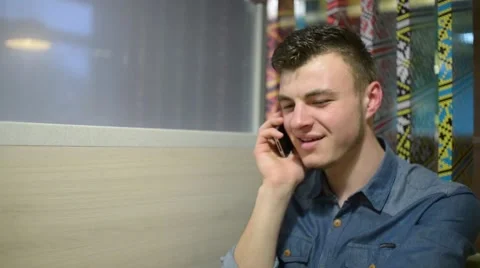A man talks with Smartphone mobile cell phone at the table cafe Stock Footage 61011288