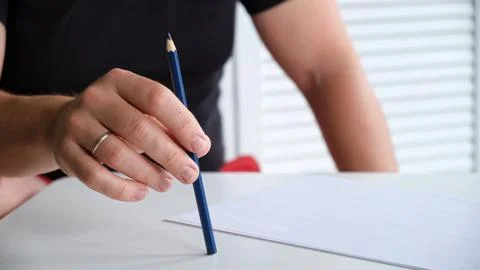 A man tapping a pen on a table with a blank sheet of paper. The concept of lack Stock-Fotos