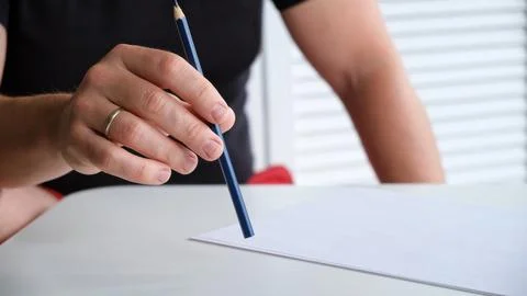 A man tapping a pen on a table with a blank sheet of paper. The concept of lack Stock-Fotos