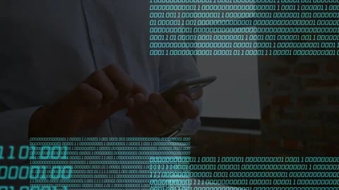 Man tapping phone with both thumbs in tech office cyan binary panels overlaying Stock Footage 334744380