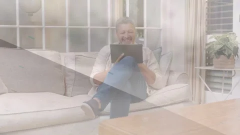 Man tapping tablet and testing tech app, smiling while soft light-leak overlay Stock Footage 333575434