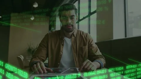 Man tapping tablet at cafe table green finance ticker sweeping revealing data Stock Footage 332625728