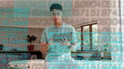 Man tapping tablet, checking tech data in room, causing teal digits overlay Stock Footage 333414102