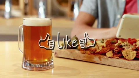 Man tapping tablet, nudging beer mug while displaying thumbs-up overlay over Video stock 310972600
