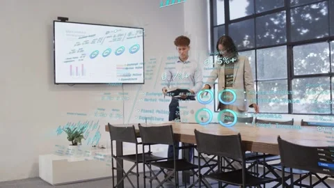Man tapping tablet showing business holo charts while woman adjusting UI and Stock Footage 333277829