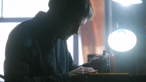 Man taps chisel with wooden mallet piercing leather sheet Stock Footage 296748997