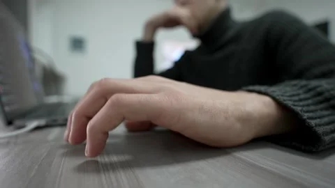 Man taps his fingers on table while sitting at his workplace near laptop. Vídeo Stock 260810646