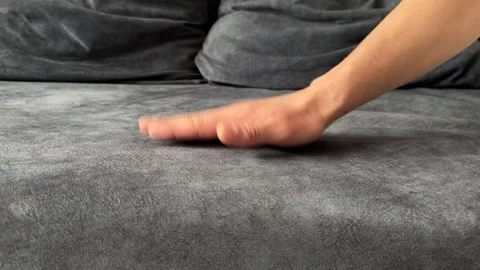 A man taps his hand rhythmically on a soft grey sofa Stock Footage 336524347