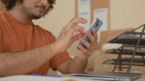 Man taps smartphone with finger while smiling at parcel and cardboard boxes.. Stock Footage 337402588