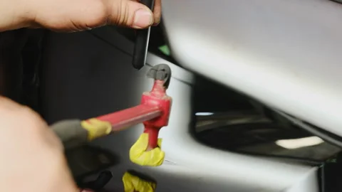 Man taps surface with slide hammer leveling surface of vehicle Stock Footage 316181434