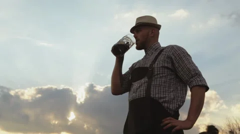 Man tasting beer on the background of the setting sun. Stock Footage 63197385