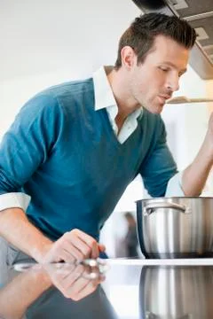 Man tasting food in the kitchen Stock Photos