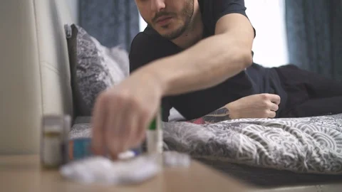 Man with tatoo using thermometer lying in bed Stock Footage 128812187
