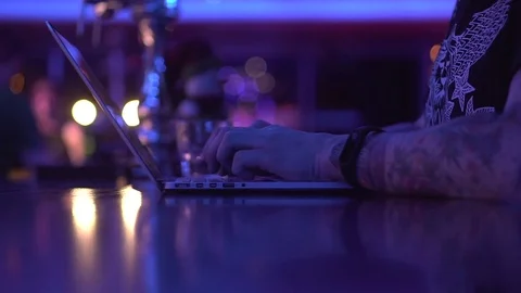 A man with a tattoo on his hands is working with a laptop. A party. Sysadmin.  Stock Footage 84530110