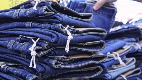 Man with tattooed hand choosing blue denim jeans in clothing store Stock Footage 343947310