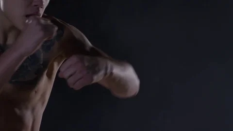 Man with tattoos boxing in a dark room with smoke. Aggressive shirtless boxer on Stock Footage
