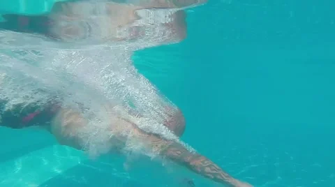 Man with tattoos dives into a swimming pool at a resort Stock Footage 45339690