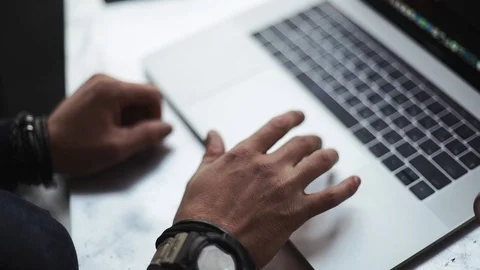 A man with tattoos on his hands is typing on a laptop Stock Footage 105483979
