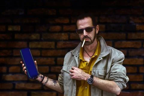 Man with tattoos posing with wireless speaker and smoking Fotos de archivo