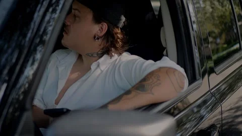 Man with tattoos sitting in car with window open, leaning... Stock Footage 324632435