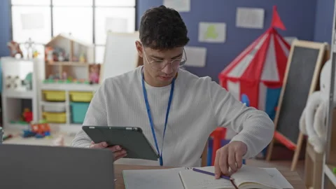 Man teacher holding tablet and writing in notebook with pencil and right ha.. Stock Footage 337376149