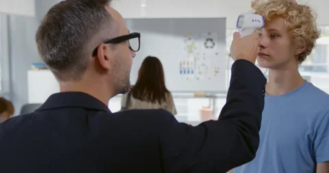 Man teacher using thermometer temperature screening student for fever against Stock Footage 243641275