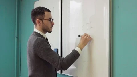 Man teacher writes on white board in class room Stock Footage 85039772