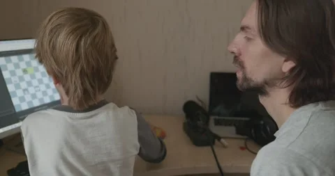 Man Teaches Kid Boy to Play Chess on Computer. 4K 10-bit Stock Footage 320170192