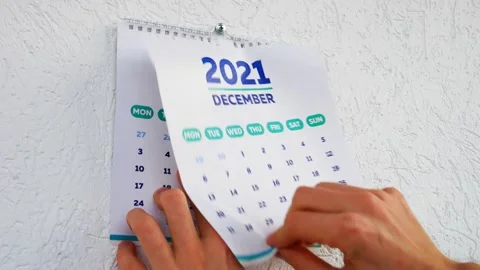 A man tears off the last page of 2021 calendar followed by the new page of 2022 Stock Footage