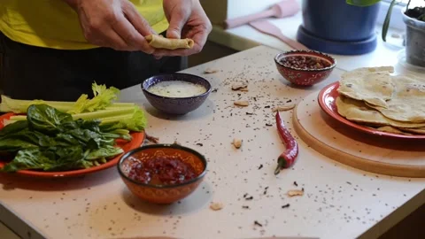 Man tears up a lenten bread dunks it into a sauce Stock Footage 86413548