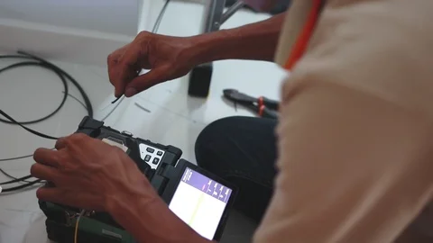 Man technician splicing two fiber optic internet cable together using a machine, Stock-Footage 102190012