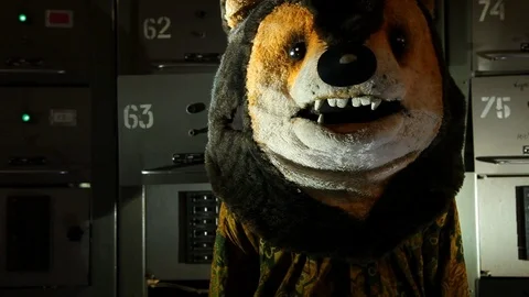 Man with a teddy bear head standing in the basement with electric boxes Stock Footage 125515799