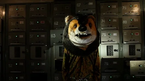 Man with a teddy bear head standing in the basement with electric boxes Stock Footage 125911359