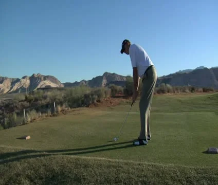 Man tees off with iron on desert golf course Stock Footage