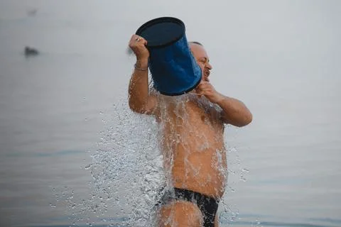 Man is tempered, dousing himself with cold water from a bucket. Stock Photos