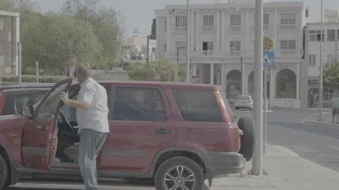 A man tending to his car in Paphos, Cyprus Stock Footage 344056320
