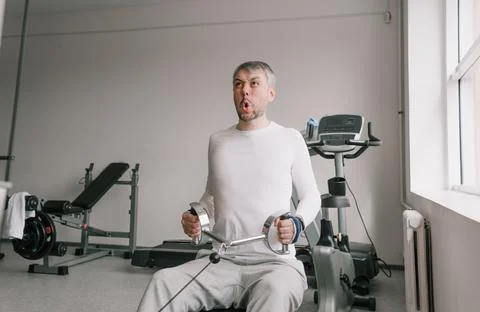 A man with a tense face performs strength training in the gym. chest cravings Stock Photos