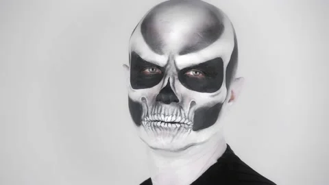 A man in a terrible Halloween skeleton make-up turns and looks at the camera Vídeo Stock 139289662