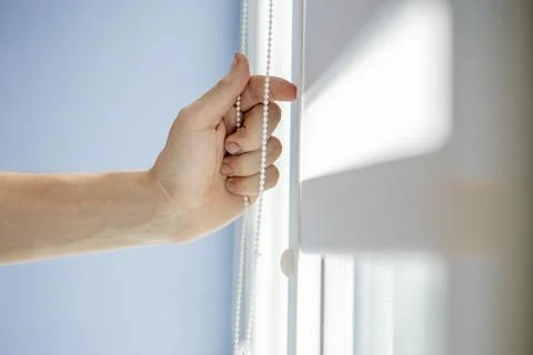 Man testing cassette roller blinds on windows. Stock Photos