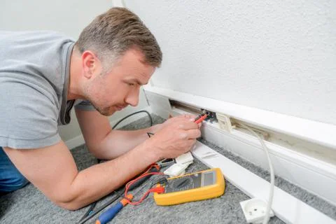 Man testing current behind skirting board Stock Photos
