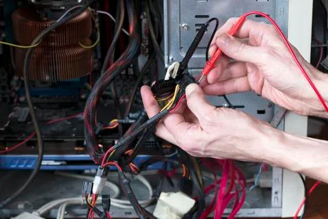 Man is testing the electrical power of power supply. Computer repair process. Stock Photos