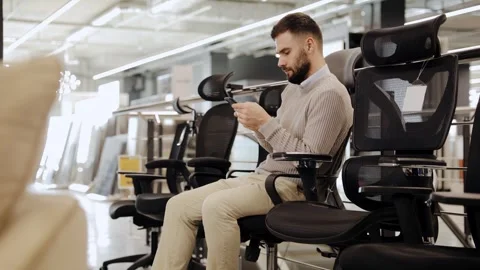 Man testing ergonomic office chair using smartphone Stock Footage 322550138