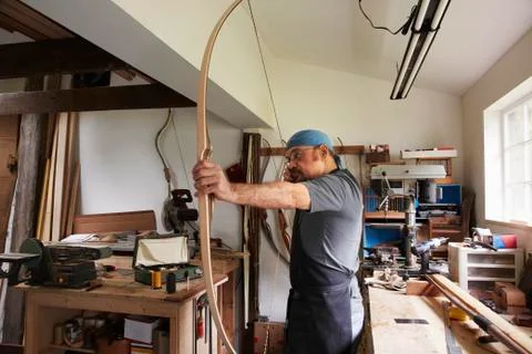 A man testing out a hand made bow by pulling the bow string. Foto stock
